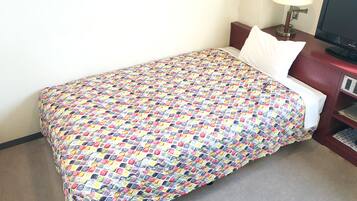 Una habitación de hotel con cama, escritorio con lámpara y televisión.