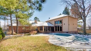 Une maison à deux étages avec un grand jardin à l’avant, une piscine et une façade en briques.