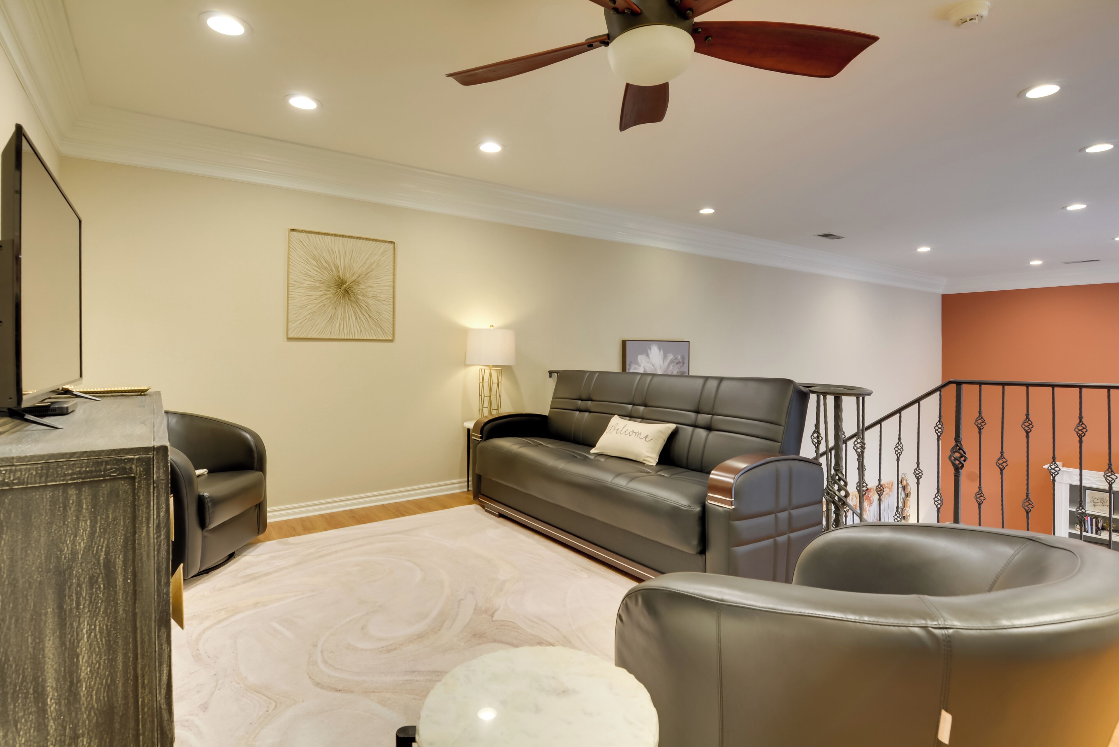 Un salon avec un canapé, une table basse, un téléviseur et un ventilateur de plafond.