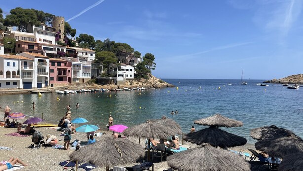 A beach with thatched umbrellas, people sunbathing, and boats in the water. - Casa Adela with private pool on walking distance to Begur. (Begur)