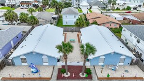 A residential area with two blue houses, a small garden, and a concrete pathway. - Sea Turtle ~ Cozy getaway less than 1/4 of a mile from the beach! (Panama City Beach)