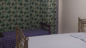 A bedroom with a bed, a wooden headboard, a patterned wall, and a tiled floor. - Hostel Vila Bela (Brasília)