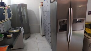 A compact kitchen with a gas stove, a refrigerator, and a water dispenser. - Hostel Vila Bela (Brasília)