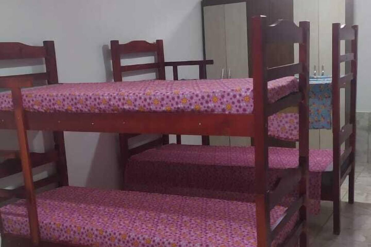 Um dormitório com beliches, um guarda-roupa e um espelho.
