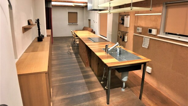 A narrow kitchen with a long wooden countertop, a sink, and a hanging light fixture. - Higashi-Gokencho M-building 2F (Tokyo)