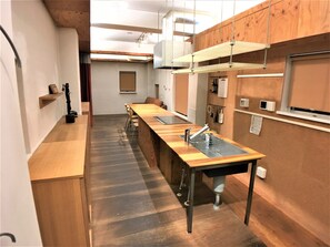 Cozinha estreita com bancada de madeira comprida, pia e luminária suspensa.