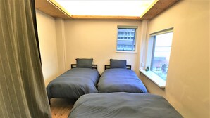 A room with two beds, a window, and a view of the outside. - Higashi-Gokencho M-building 2F (Tokyo)