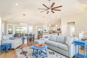 A spacious living room with a gray sectional sofa, a blue coffee table, and a ceiling fan.