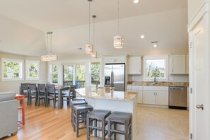 A spacious kitchen with a central island, bar stools, and a dining area with chairs.