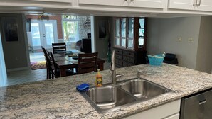 A kitchen with granite countertops, a stainless steel sink, and white cabinets. - Spacious 3 BR 2 Bath  House On Deep Canal With Screened Heated Pool  (Crystal River)