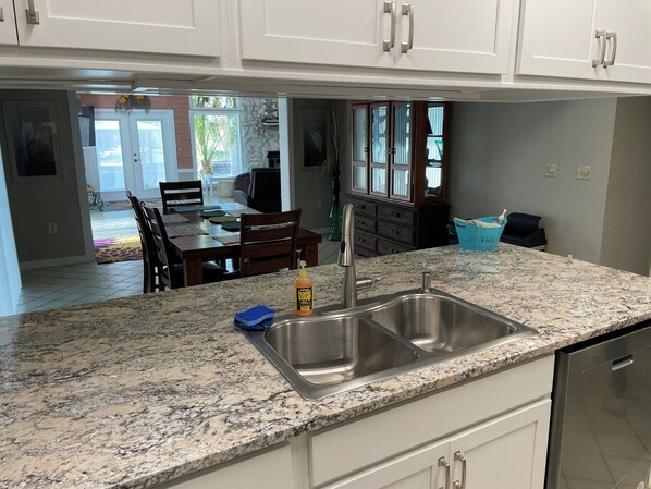 A kitchen with granite countertops, a stainless steel sink, and white cabinets.