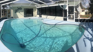 A swimming pool with clear water, surrounded by a covered area with a roof and glass walls. - Spacious 3 BR 2 Bath  House On Deep Canal With Screened Heated Pool  (Crystal River)
