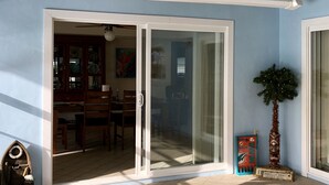 A room with a sliding glass door leading to a dining area, a small indoor plant, and a decorative wooden structure. - Spacious 3 BR 2 Bath  House On Deep Canal With Screened Heated Pool  (Crystal River)
