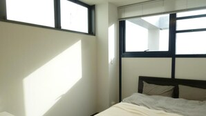 Un dormitorio con cama, mesita de noche y ventana con persianas.