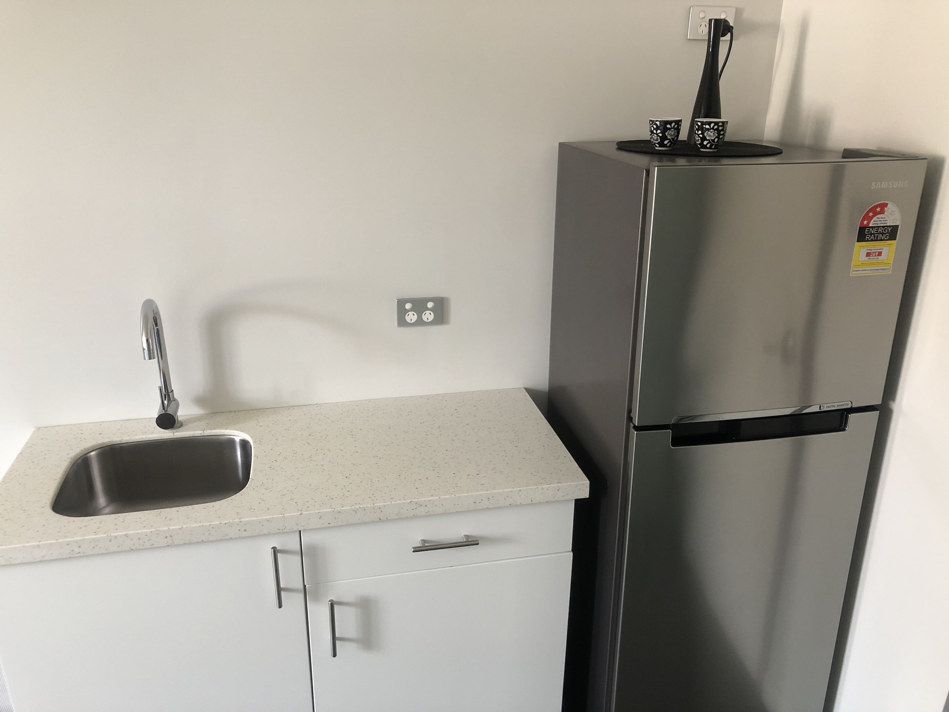 Una cocina con un refrigerador de acero inoxidable, un lavamanos y una encimera.