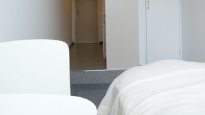 Una habitación de hotel con una cama, una mesita y una puerta que da a otra estancia.