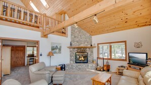 A spacious living area with a stone fireplace, wooden ceiling, and a television. - Lakefront cabin on Minong Flowage (Minong)