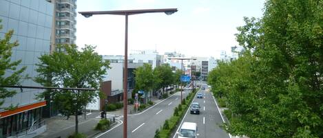 A multi-lane urban road with cars, a pedestrian crossing, and buildings on both sides.
