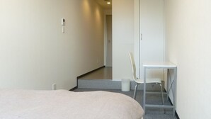 Habitación de hotel con una cama grande, un escritorio y una silla. Una escalera conduce a otra habitación.