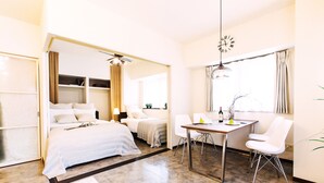 A modern hotel room with a bed, a dining table with chairs, a small kitchen area, and a large window. - City Hotel Namba Ⅱ (Osaka)