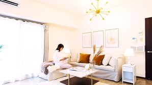 A modern living room with a sofa, coffee table, and a person reading a magazine. - City Hotel Namba Ⅱ (Osaka)