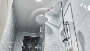 A modern bathroom with a shower, tiled walls, and a visible door. - 30 month HOTEL (Seoul)