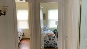 A hallway with wooden flooring leading to a bedroom with a bed and a window. - Residential Bungalow - Pet friendly, WiFi, Quiet Residential Area (Norfolk)