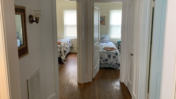 A hallway leading to two bedrooms with wooden flooring and white walls. - Residential Bungalow - Pet friendly, WiFi, Quiet Residential Area (Norfolk)
