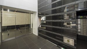 A modern interior with reflective glass walls, a tiled floor, and a sign indicating a business center. - City Hotel Shinsaibashi (Osaka)