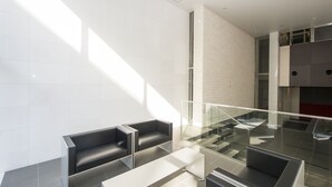 A modern lobby with a glass railing, a staircase, and a seating area with black sofas. - City Hotel Shinsaibashi (Osaka)
