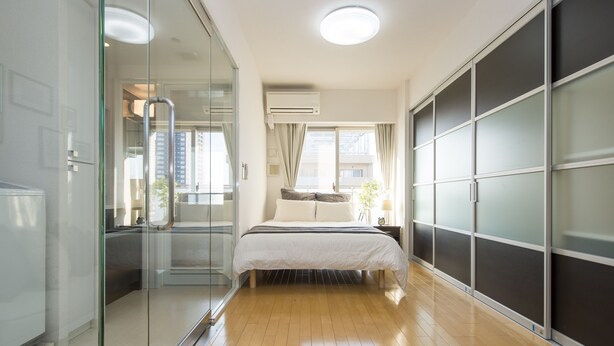 A bedroom with a bed, a glass partition, a sliding door, and a window. - City Hotel Shinsaibashi (Osaka)