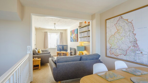 Een woonkamer met een bank, televisie en een kaart aan de muur.