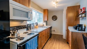 Une cuisine moderne avec des meubles en bois, une cuisinière blanche, un four à micro-ondes et un évier.