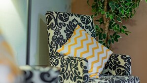 Une chaise recouverte d’un tissu à motifs géométriques noir et blanc, agrémentée d’un coussin jaune à chevrons.