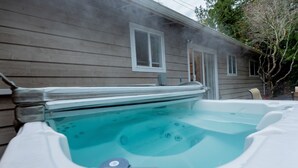 Un jacuzzi situé à côté d’une maison, avec une fenêtre et une porte.