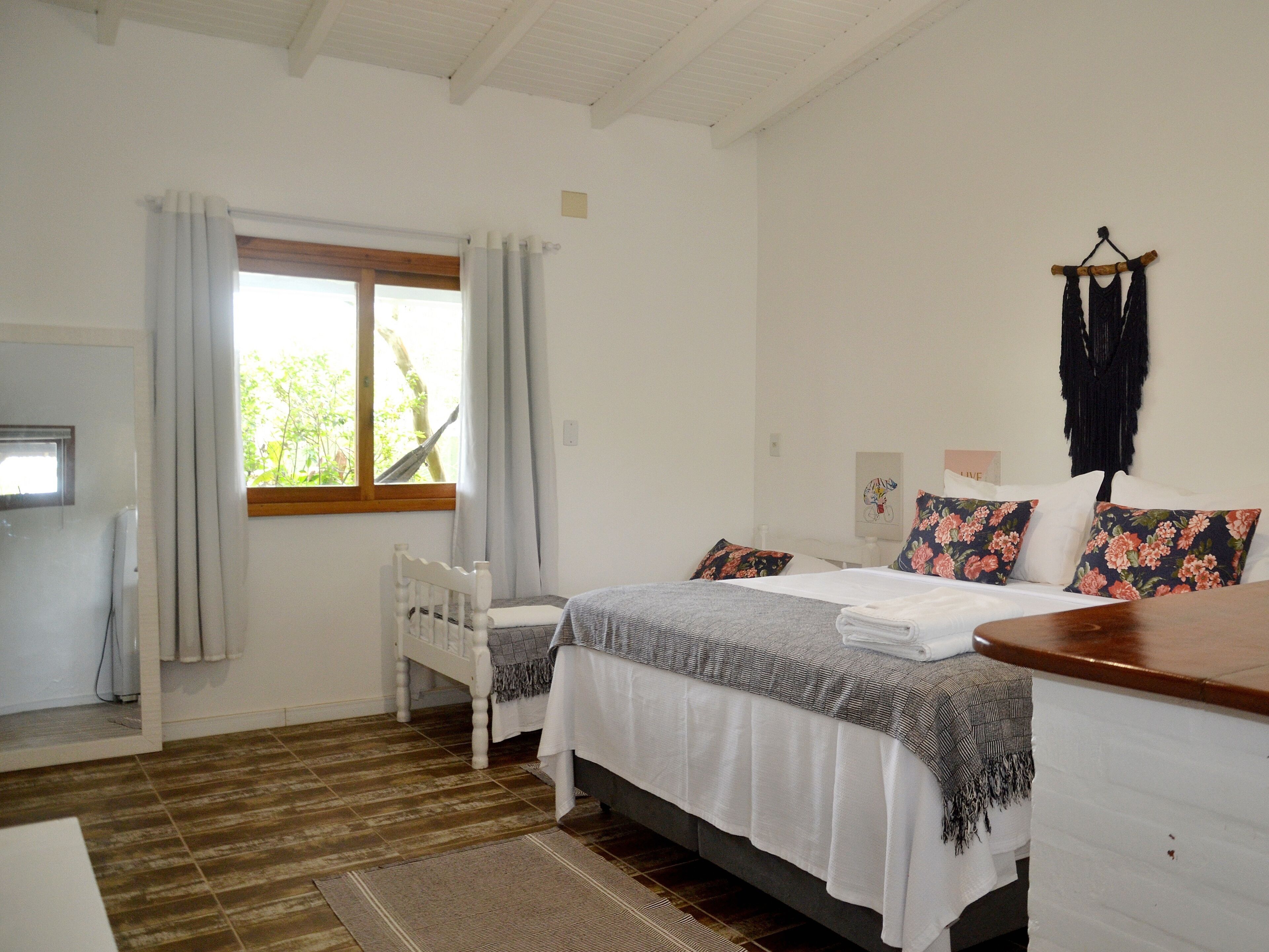 A bedroom with a bed, a chair, a window, and a wooden headboard.