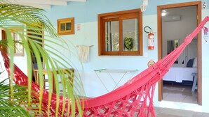 A room with a hammock, a window, a fire extinguisher, and a door leading to another room. - Pousada la Boheme (Palhoça)