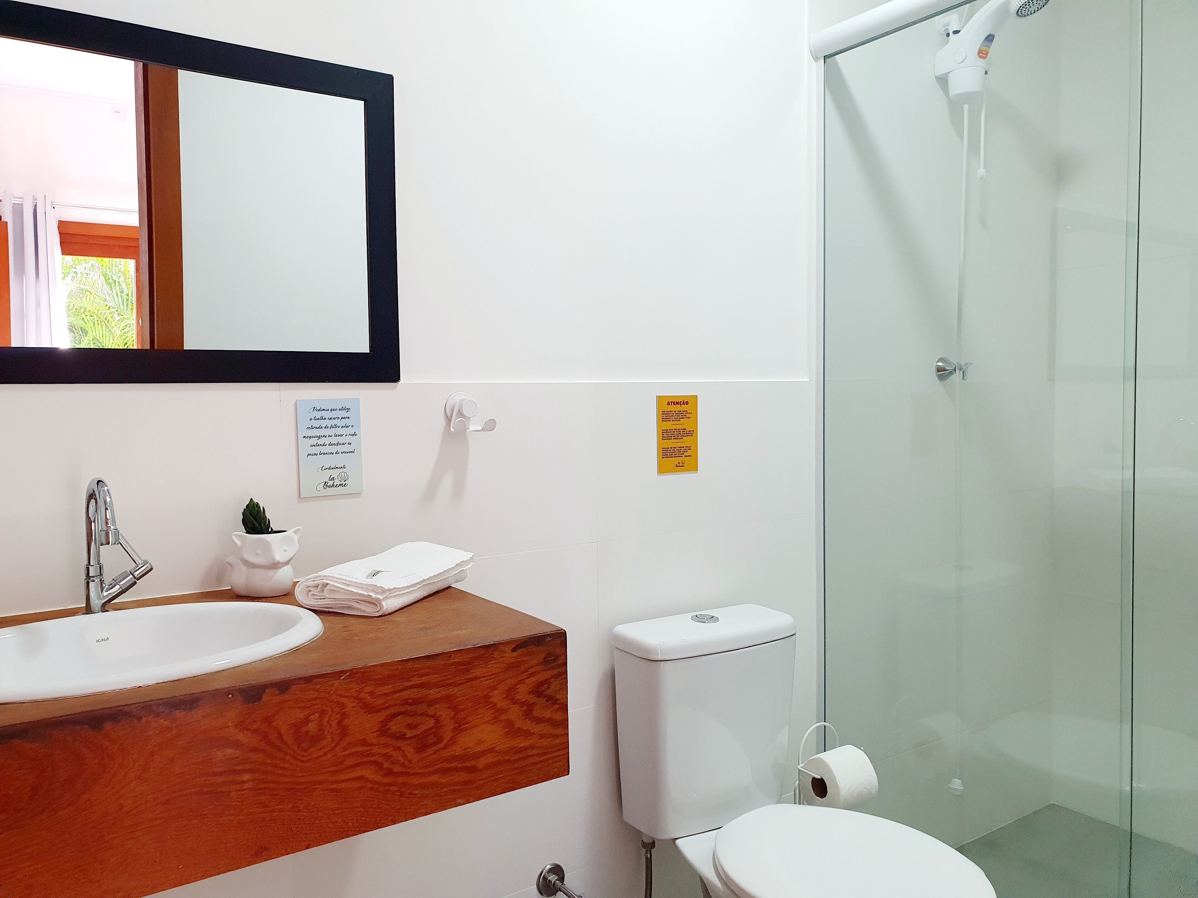 A modern bathroom with a wooden vanity, a white sink, a toilet, and a glass shower enclosure.