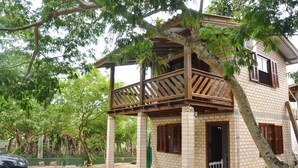 A two-story building with a balcony, brick walls, and a covered porch. - Pousada la Boheme (Palhoça)