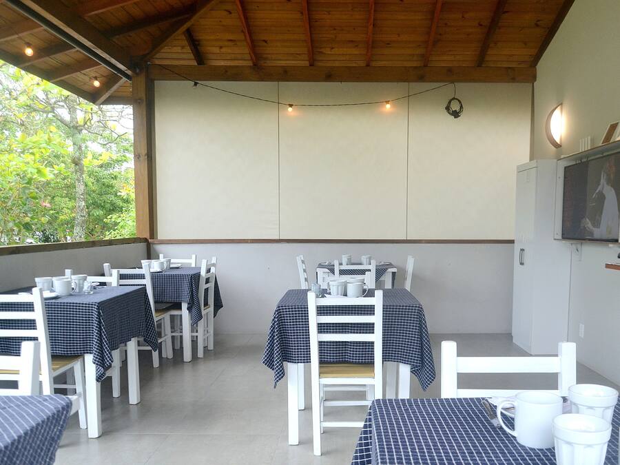 An outdoor dining area with tables and chairs, string lights, and a wall-mounted television.
