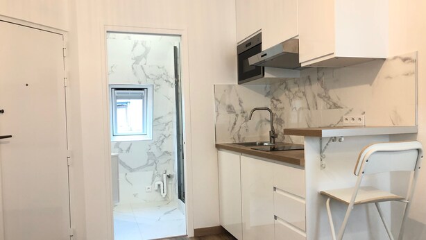 A modern kitchen with white cabinets, a marble backsplash, and a stainless steel sink. - Brand new studio located in the center of Paris (Paris)