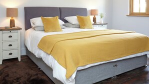 A bedroom with a bed, two bedside tables, a nightstand, a window, and a wall-mounted lamp. - 1 bedroom accommodation in Brighstone (Brighstone)