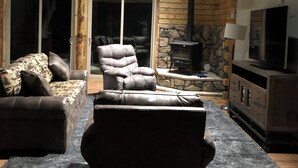 A cozy living room with a stone fireplace, leather sofas, and a television. - Lookout cabin (Kamiah)