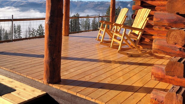 A wooden deck with two rocking chairs, a metal railing, and a view of a mountainous landscape. - Lookout cabin (Kamiah)