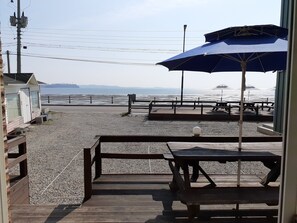 A beachside patio with wooden benches and tables, overlooking the sea. - Jebudo Yeonliji Pension (Hwaseong)