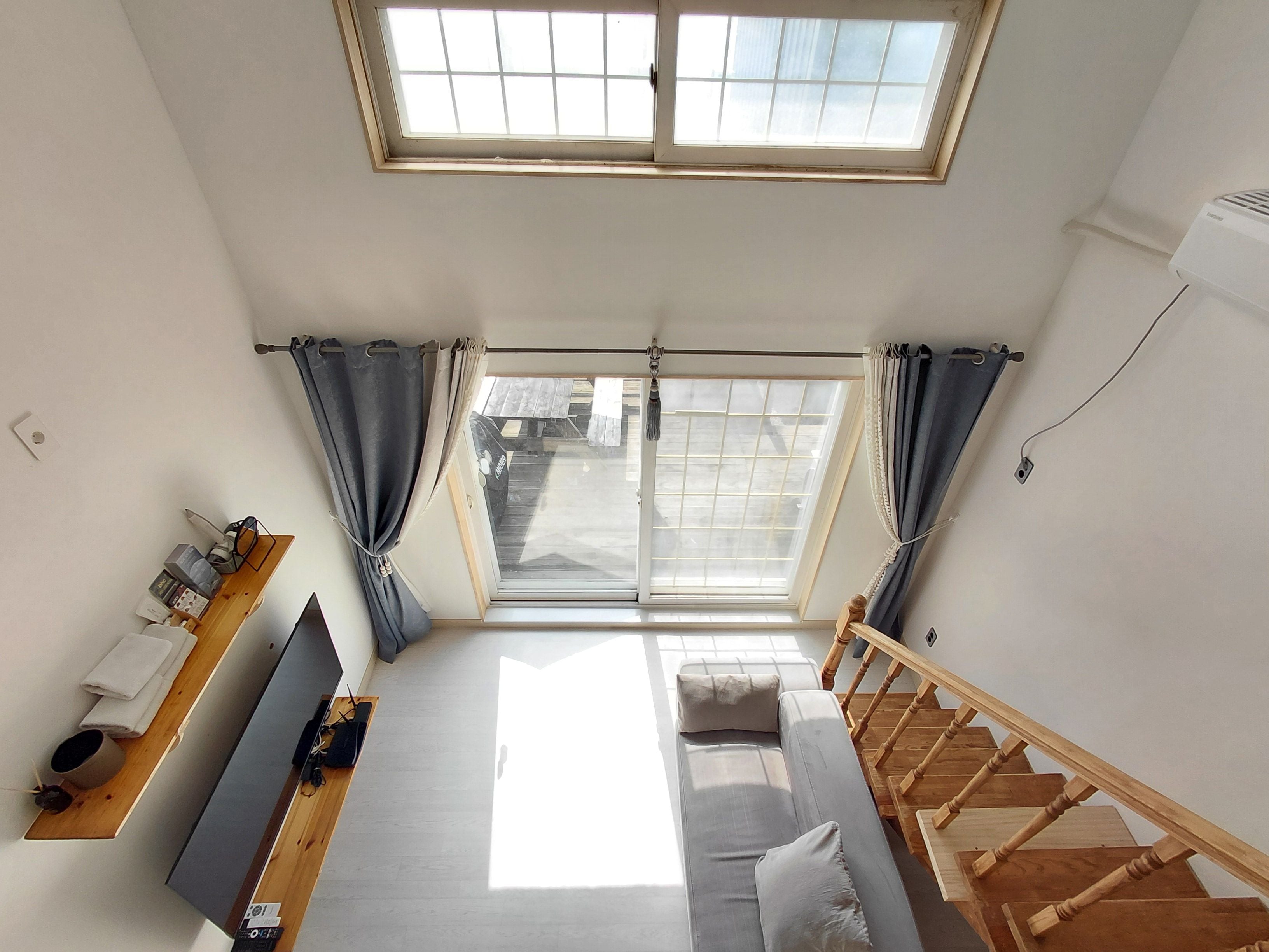 A room with a bed, a TV, a desk, a window, and a staircase.