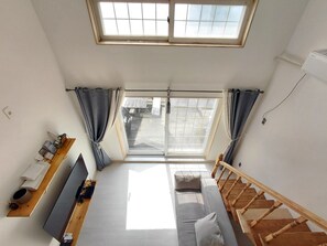Une pièce comprenant un lit, une télévision, un bureau, une fenêtre et un escalier.
