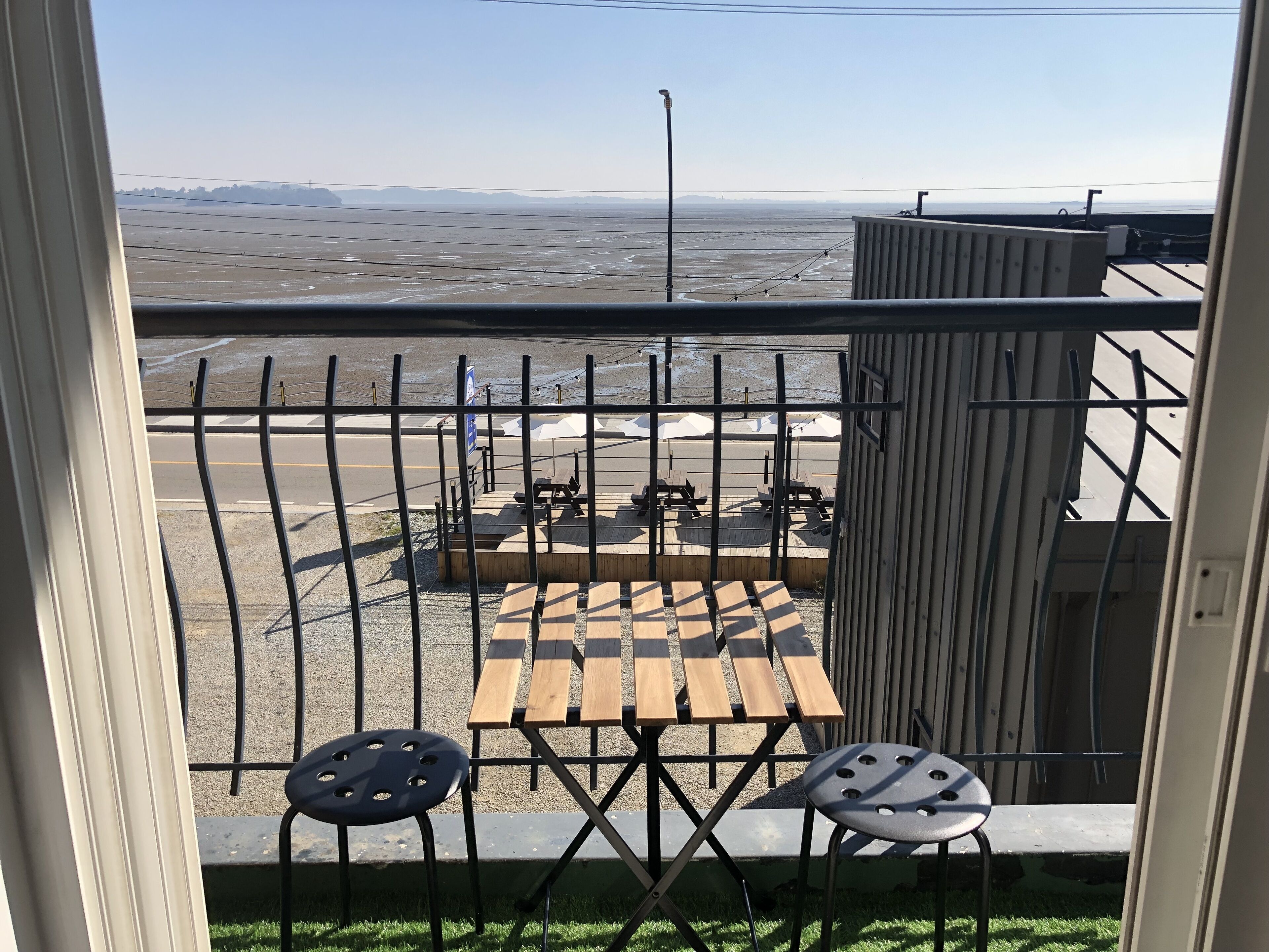 A balcony with a view of a parking lot and distant mountains.