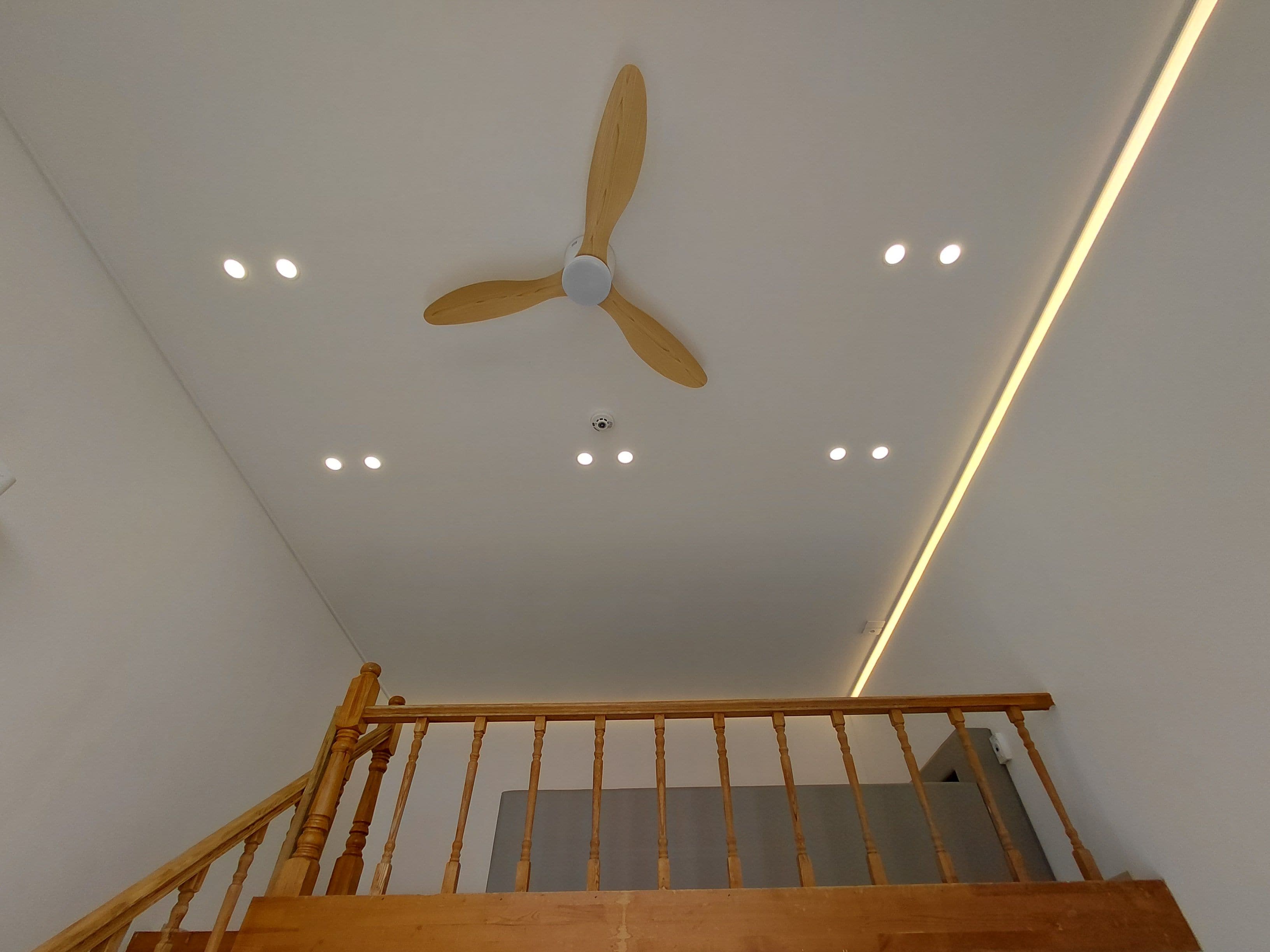 A ceiling fan with wooden blades and recessed lighting.