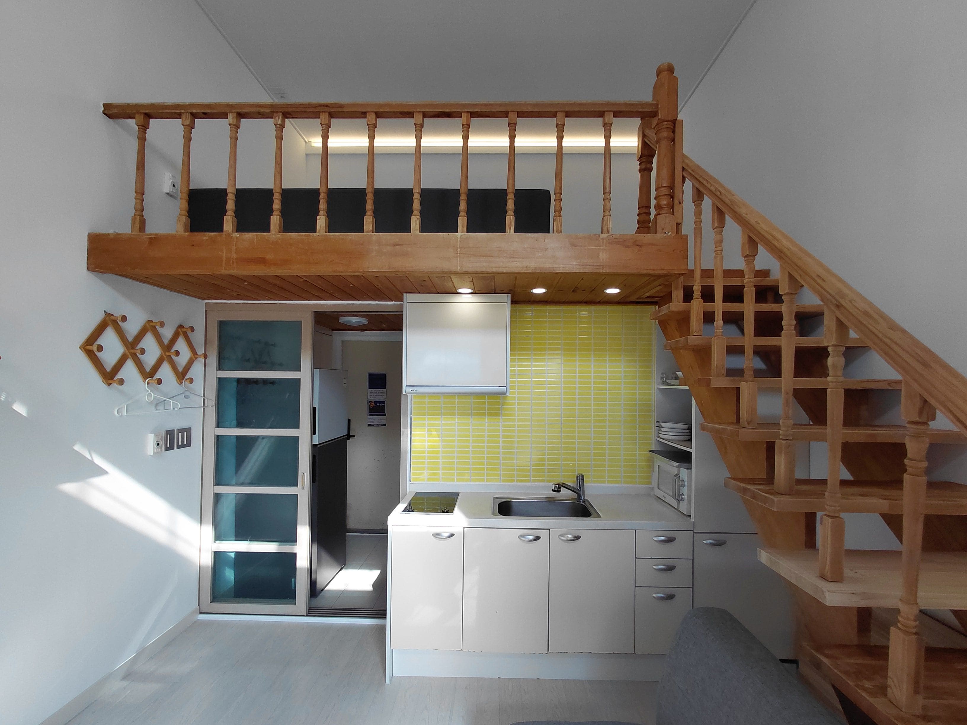 Una cocina compacta con escalera de madera, lavamanos empotrado y armarios.